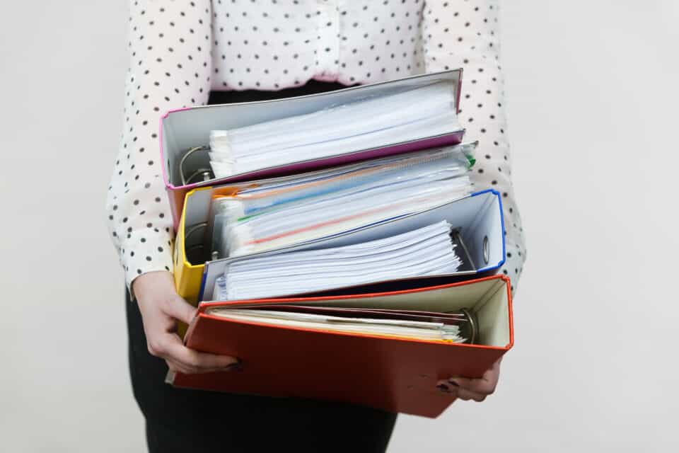Woman Holding Heavy Colorful Binders With Documents